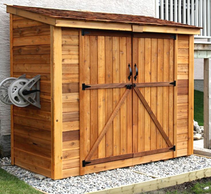 a wooden storage shed sitting in the grass