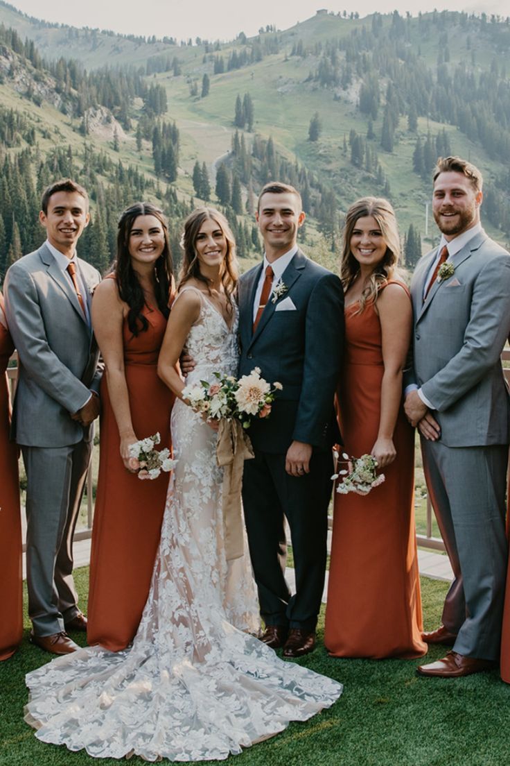 a group of people standing next to each other in front of a lush green hillside