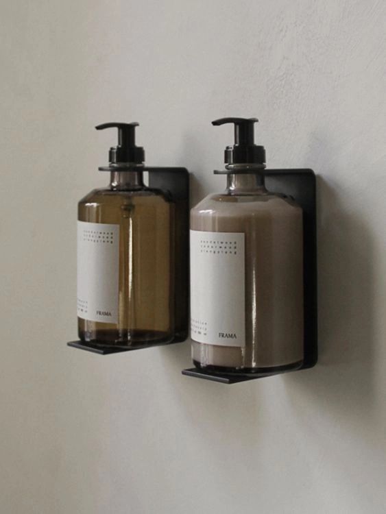 two soap dispensers are hanging on the wall next to each other,