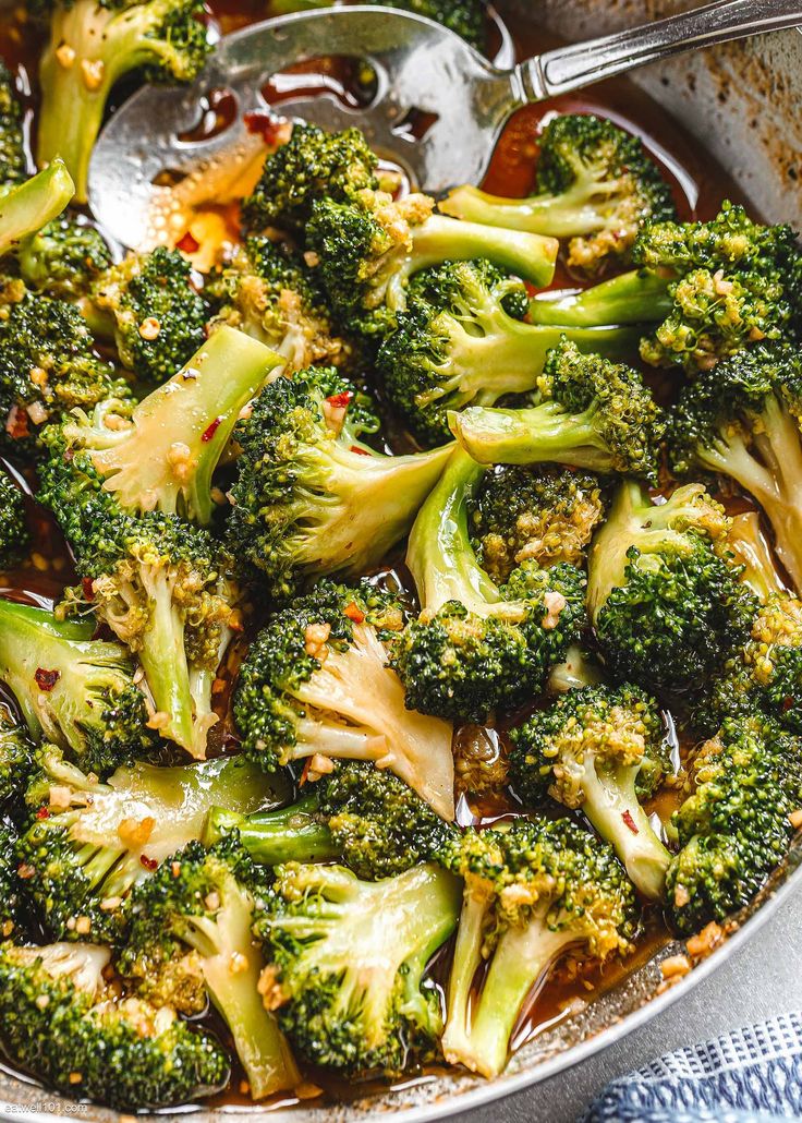 broccoli florets are being cooked in a skillet with spoons