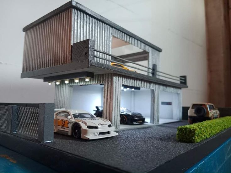 a toy car is parked in front of a model house with cars on the driveway