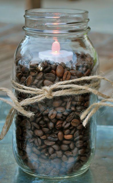 a glass jar filled with coffee beans and a lit candle