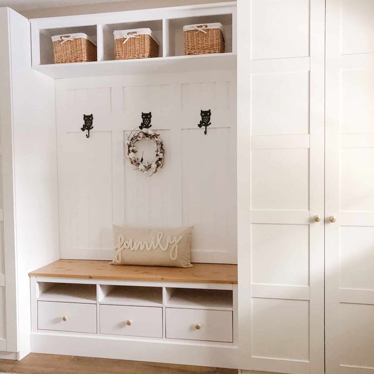 an entryway with white cabinets and baskets on the wall, along with a wooden bench