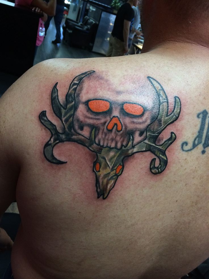 a man with a skull and antlers tattoo on his back