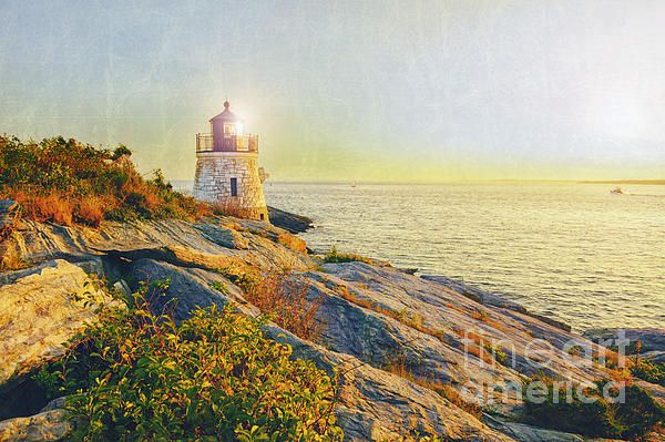 a light house sitting on top of a rocky cliff next to the ocean at sunset