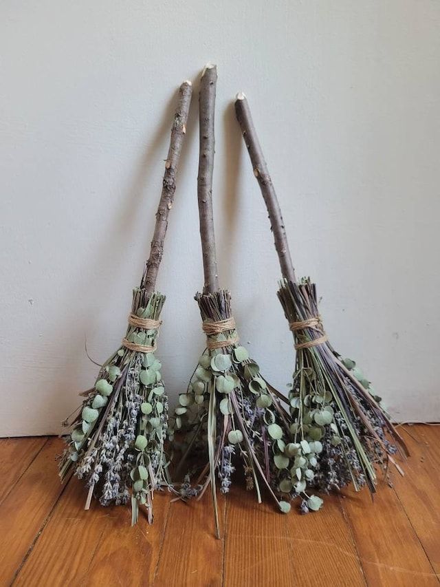 three twigs with flowers tied to them sitting on a wooden floor next to a wall