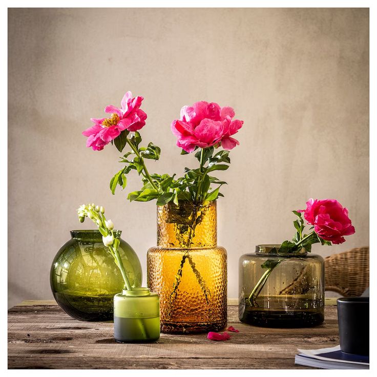 three vases with flowers in them sitting on a table