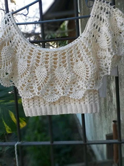 a crocheted top hanging on a fence