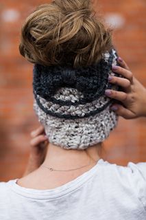 a woman wearing a crocheted headband with her hair in the air,