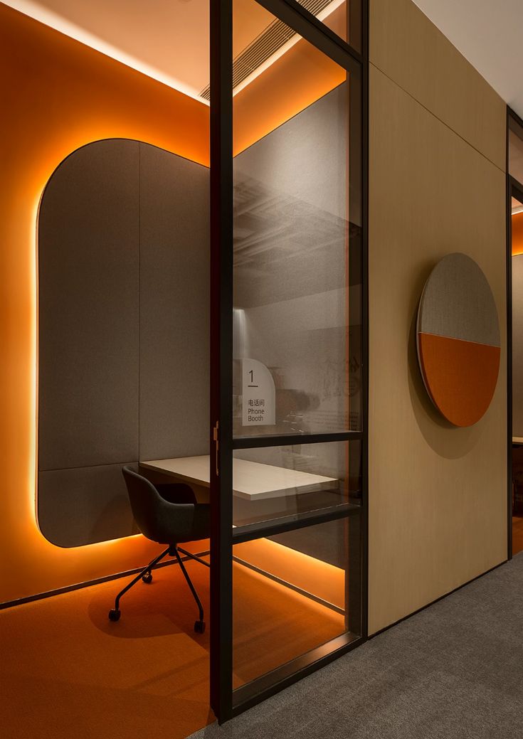 an office with orange lighting and a round mirror on the wall next to a desk