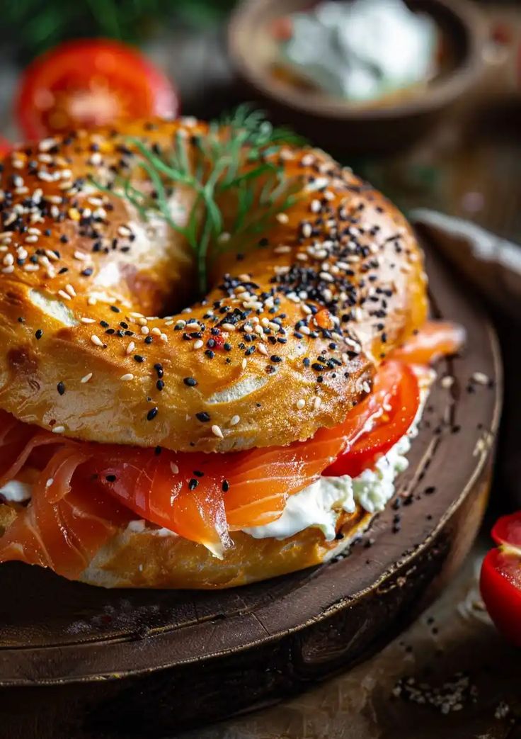 a bagel sandwich with salmon, cheese and tomato slices on a wooden platter