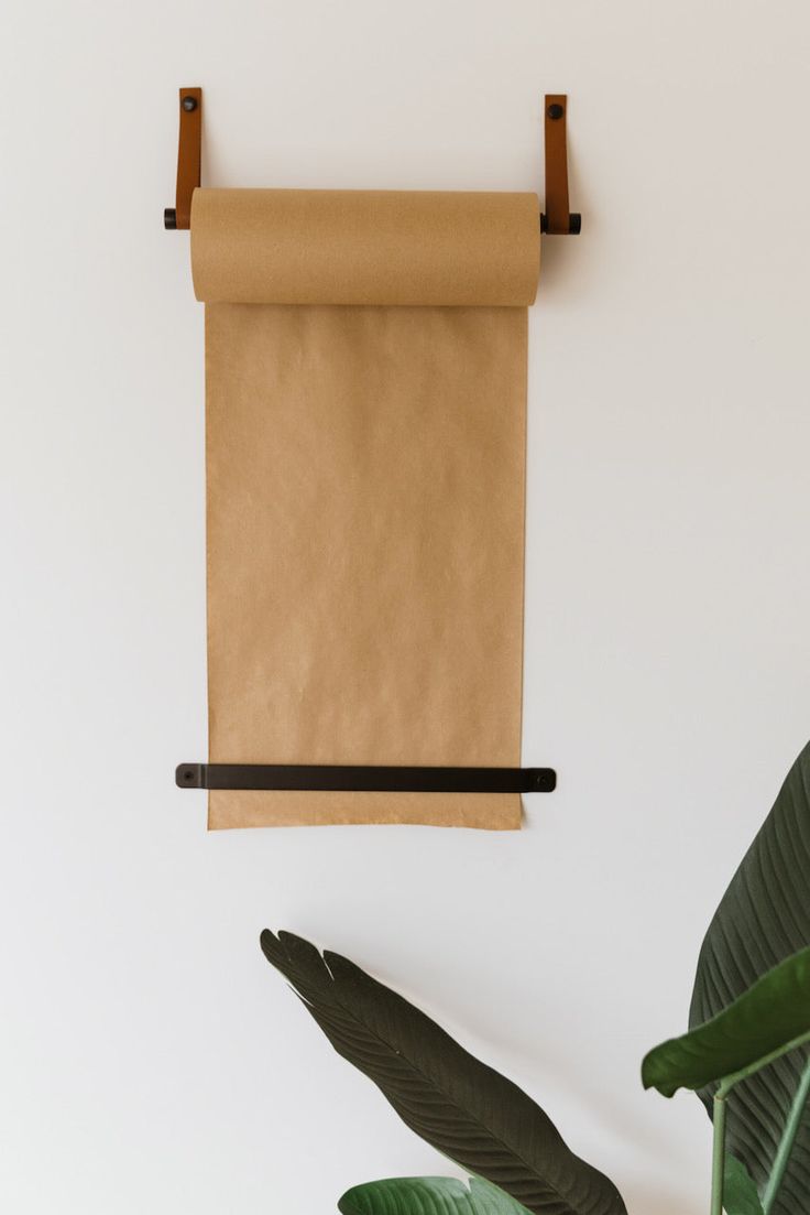 a brown paper towel hanging on a wall next to a green plant and a potted plant