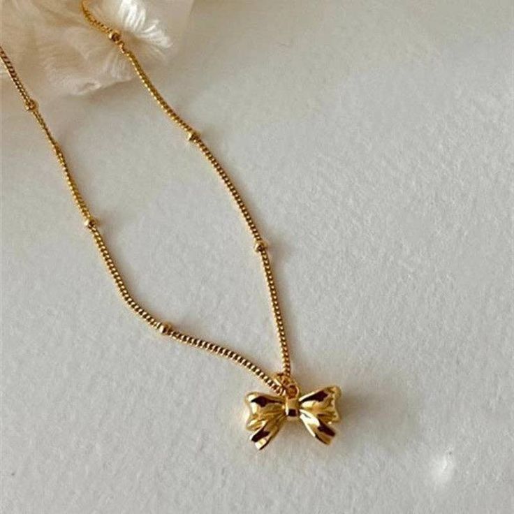 Tie your outfit together with our Bowknot Charm Necklace. This playful accessory features a charming bowknot design in both silver and gold, adding a touch of whimsy to your look. Bring some fun to your style and make a statement with this unique necklace. Gold Butterfly Knot Necklace For Gift, Gold Necklaces With Butterfly Knot For Gift, Gold Necklace With Butterfly Knot For Gift, Feminine Bow Necklace For Party, Gold Necklaces With Bow Detail, Gold Necklace With Bow For Party, Gold Bow Necklace For Party, Elegant Gold Necklace With Decorative Bow, Chic Ribbon Necklace For Gift