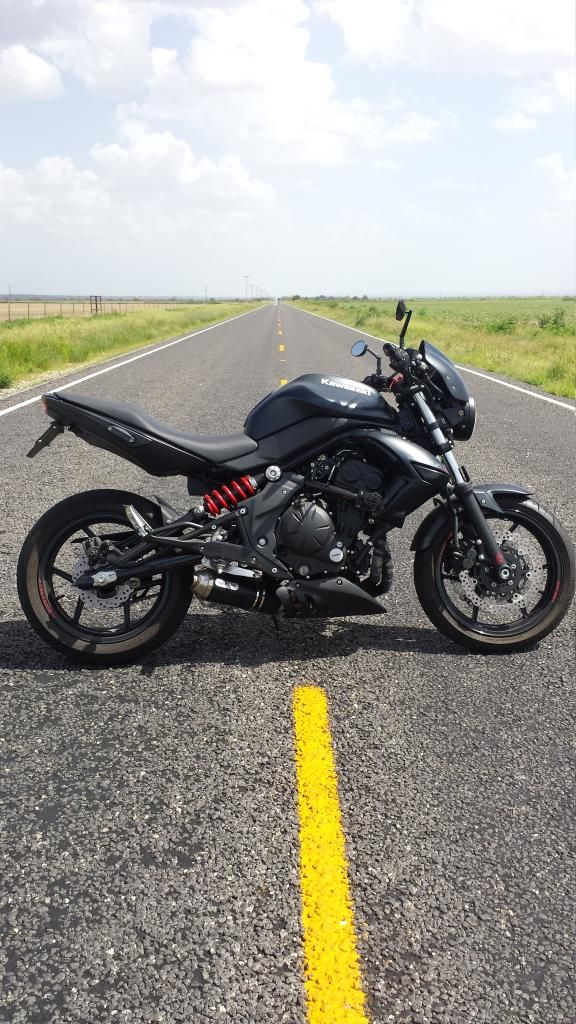 a motorcycle is parked on the side of an empty road with grass in the background