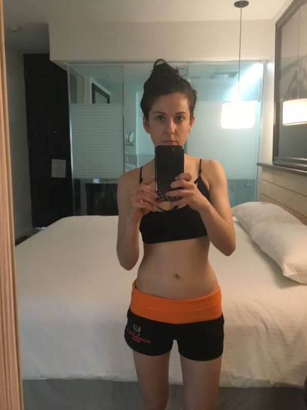 a woman taking a selfie in front of a mirror with her cell phone and wearing shorts