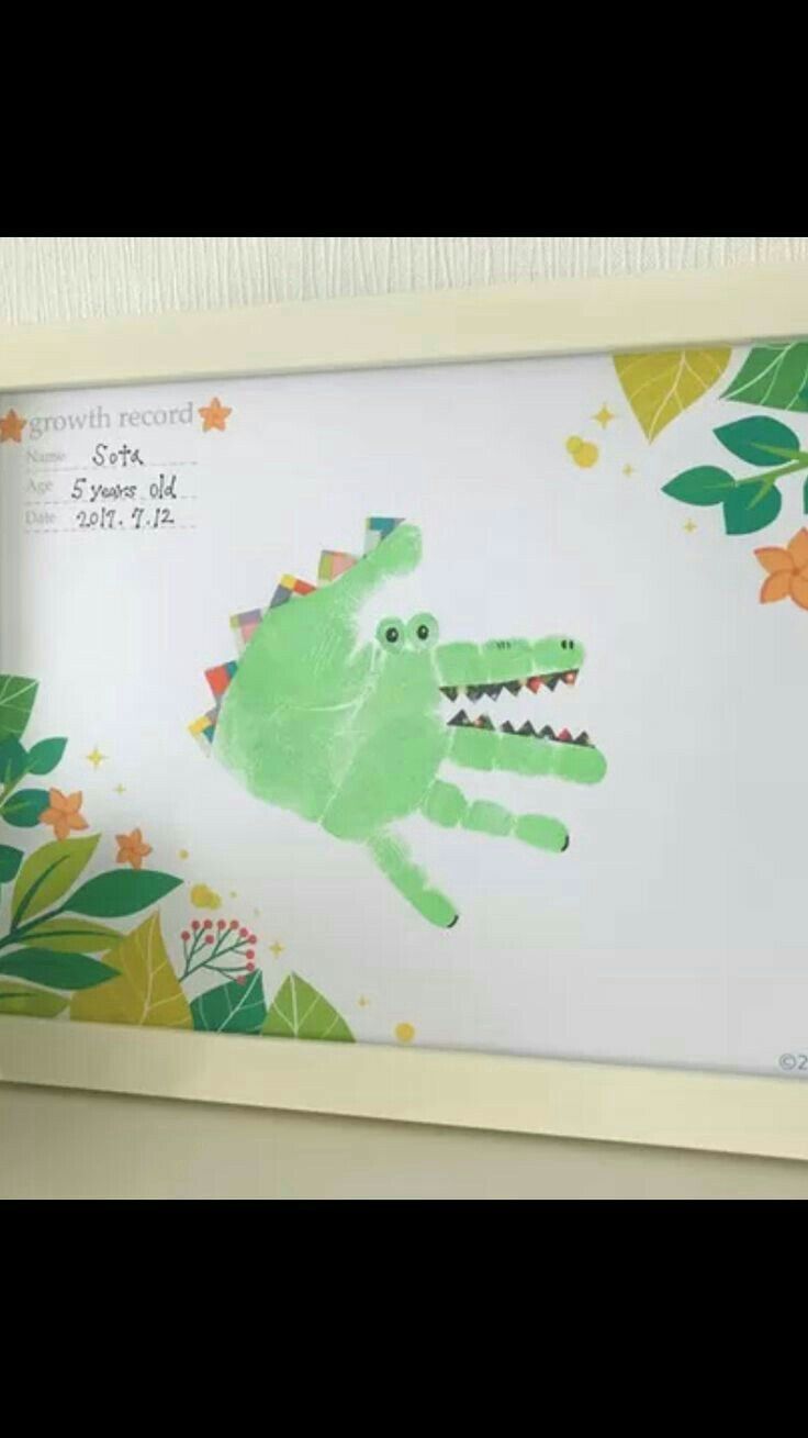 a child's drawing of a green alligator in front of a white background with leaves and flowers