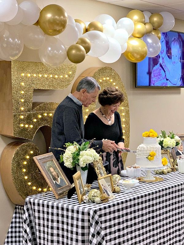 a man and woman standing in front of a table with a cake on top of it