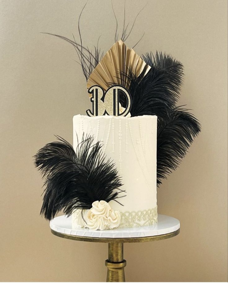 a white cake with black feathers and a monogram on top