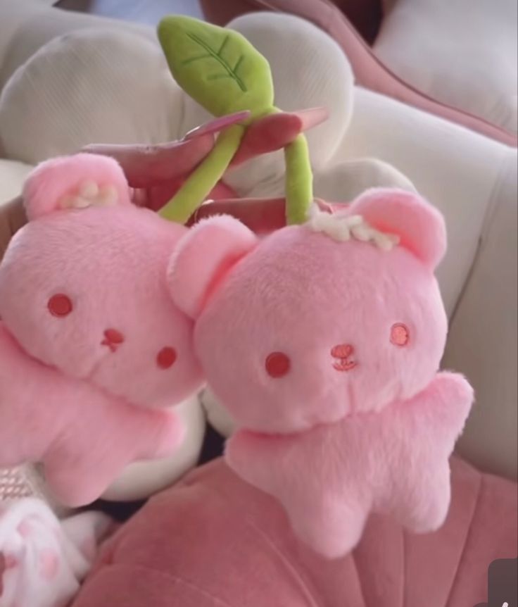 two pink teddy bears are hanging from a hook on a stuffed animal car seat cover