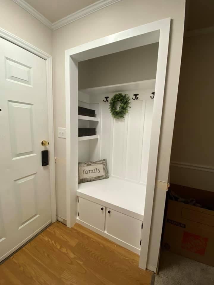 an empty room with a white door and some shelves in the corner that have books on them