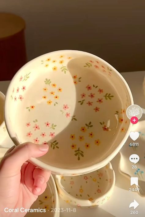 a person is holding a bowl in front of some cups and saucers on a table