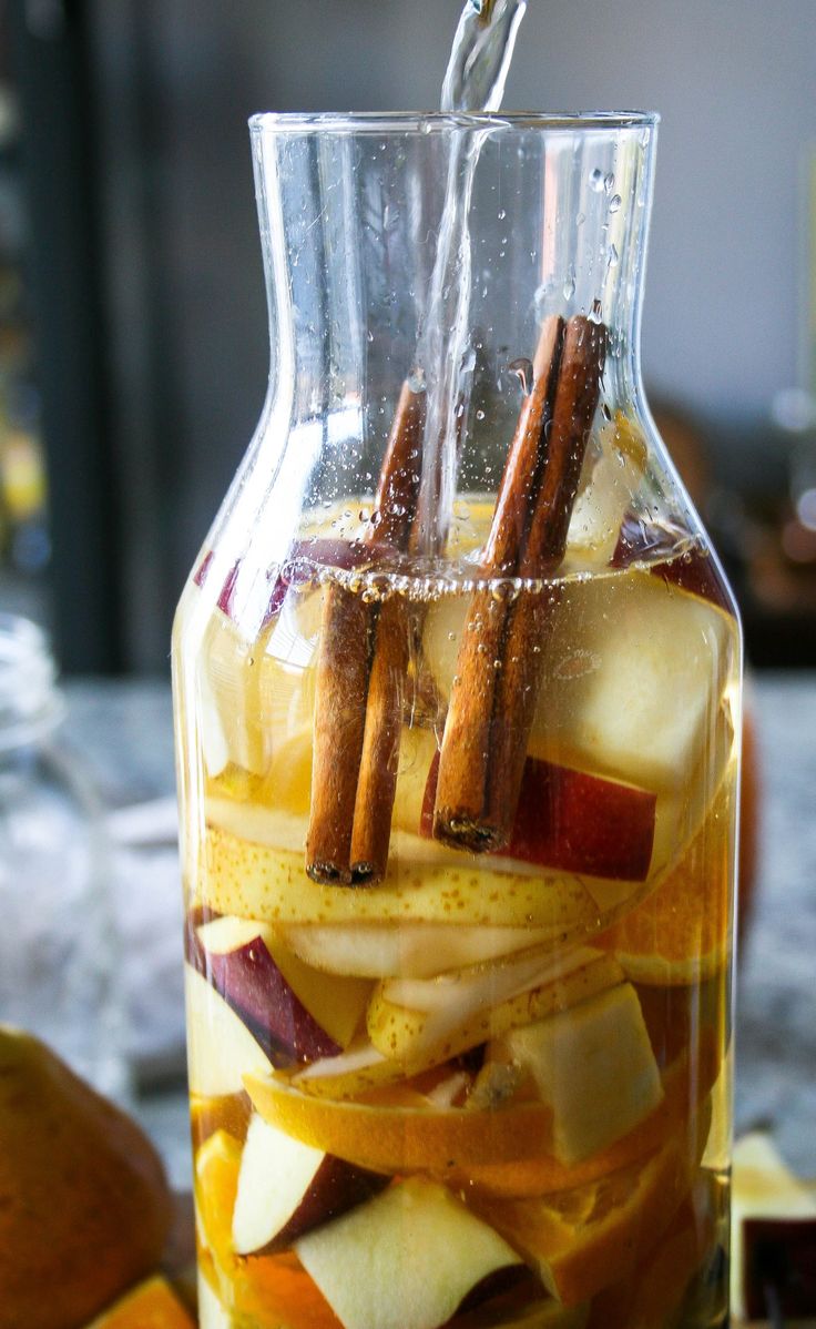 a pitcher filled with sliced apples and cinnamon sticks