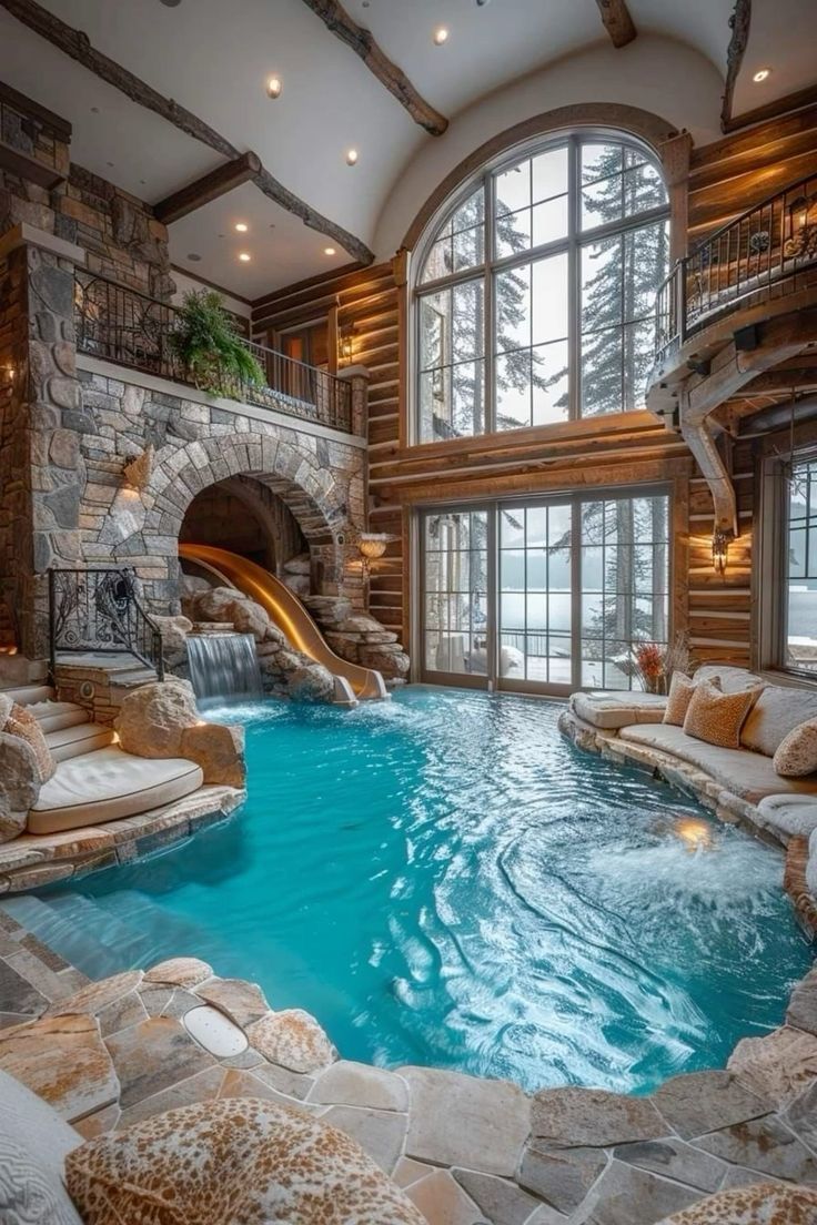 an indoor swimming pool with waterfall and slide in the middle, surrounded by stone walls