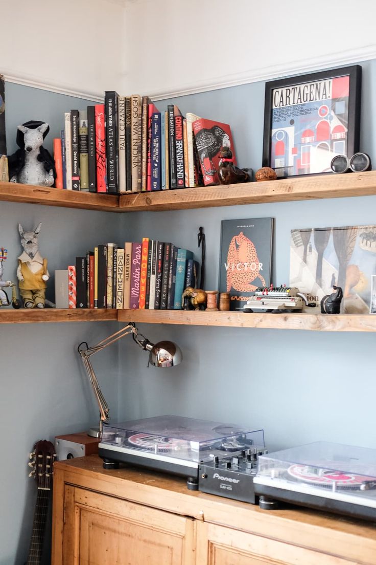 a record player sitting on top of a wooden cabinet next to a shelf filled with books