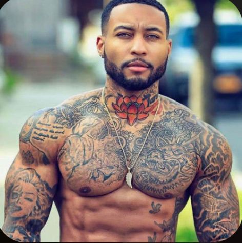 a shirtless man with tattoos on his chest and chest is looking at the camera