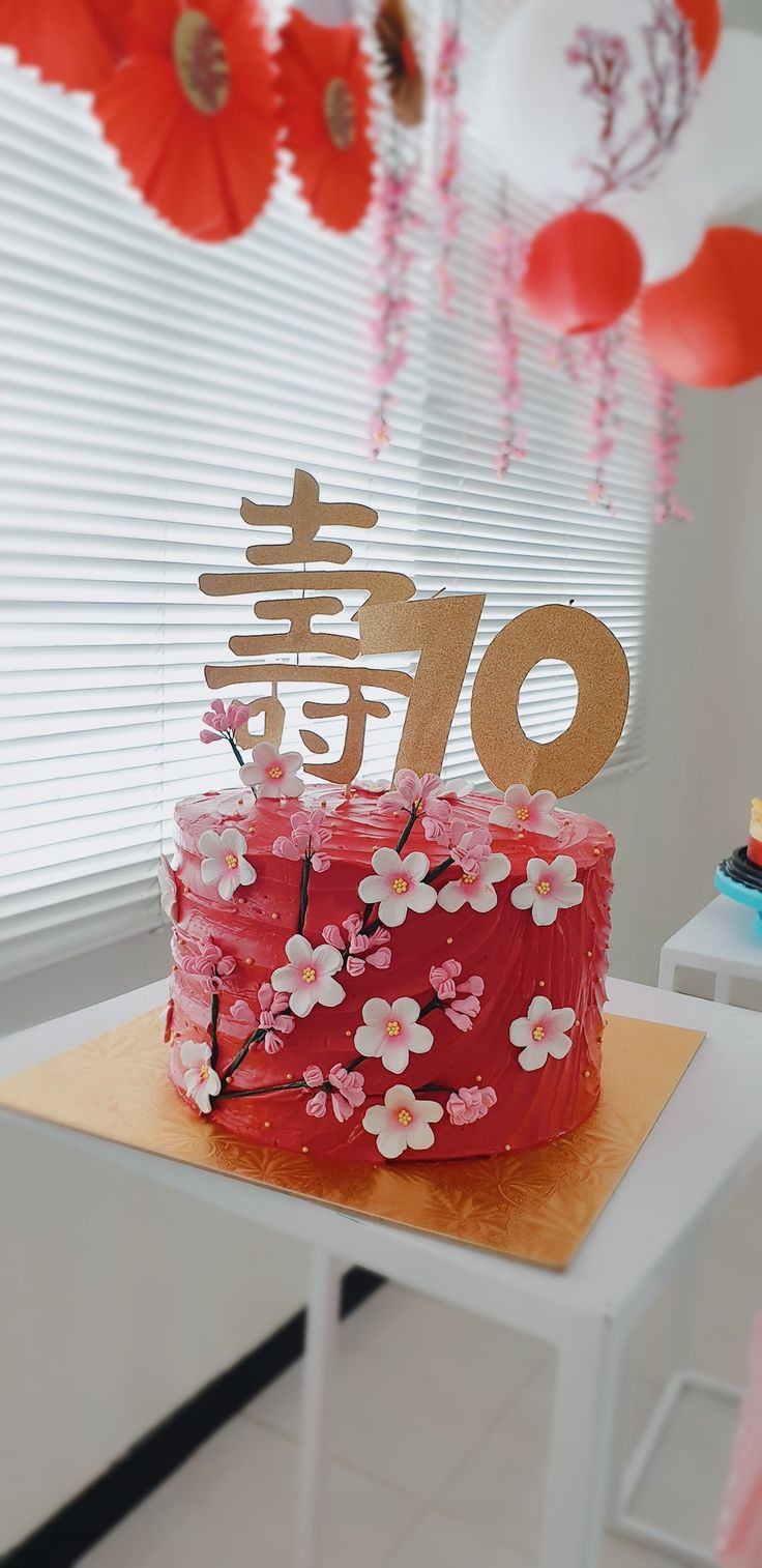 a red cake with white flowers and chinese characters on top is sitting on a table