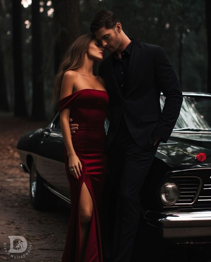 a man and woman standing next to each other in front of a car