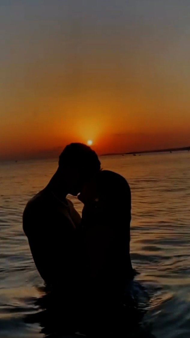 a man sitting in the water at sunset with his head on his hands while looking into the distance