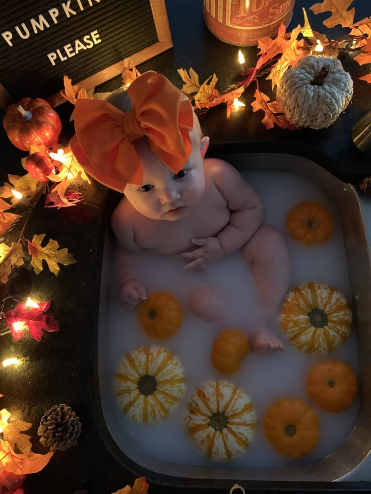 a baby in a bathtub surrounded by pumpkins