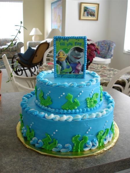 there is a blue cake with green decorations on the top and bottom, along with a picture frame