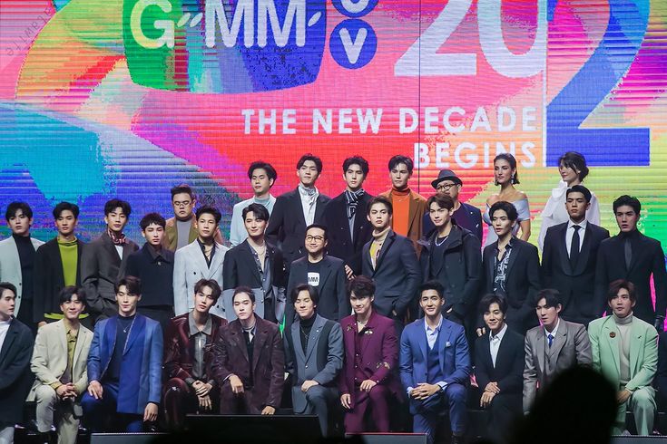 a large group of people standing on stage in front of a colorful wall with the words gumm's 205