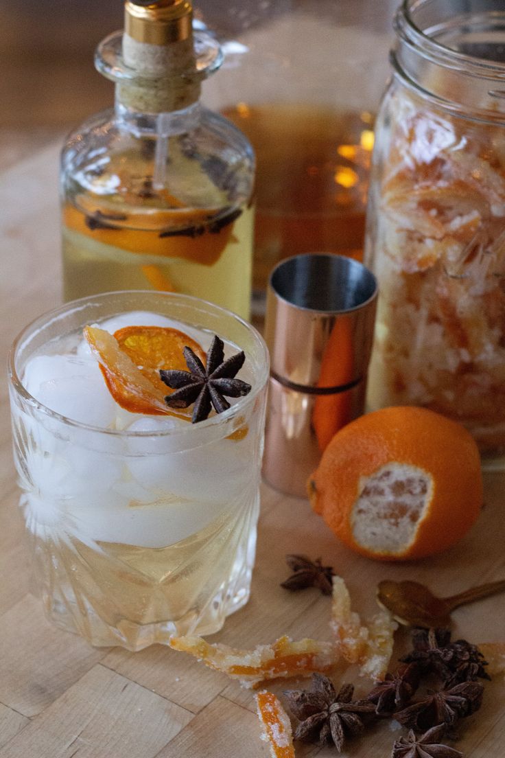 an orange and spices sit on a table next to some bottles with liquor in them