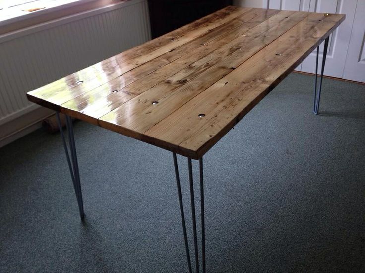 a wooden table with hairpin legs in a room next to a wall and window