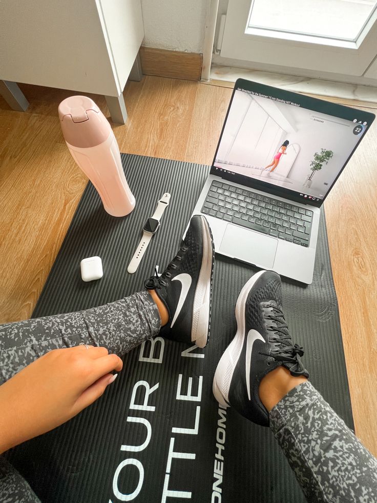 a person sitting on a yoga mat with their feet up in front of a laptop