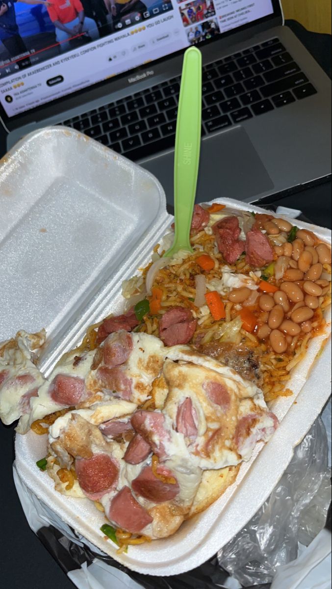 a laptop computer sitting on top of a desk next to a tray with food in front of it