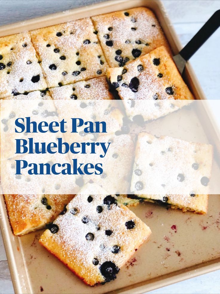 sheet pan blueberry pancakes with powdered sugar on top and blackberries in the middle