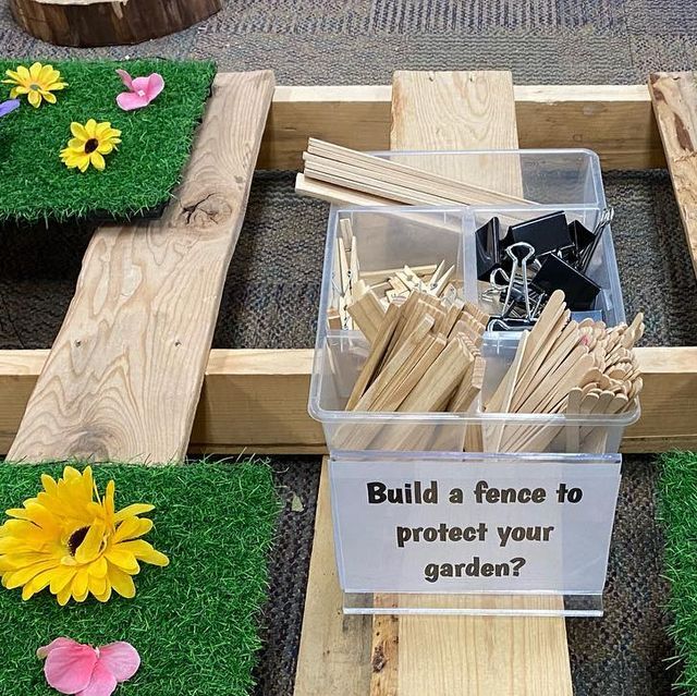 a box filled with sticks and flowers on top of green grass next to wooden planks