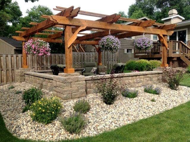 an outdoor patio with stone walls and wooden pergols on the side of it