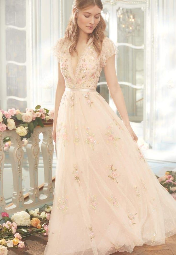 a woman in a pink dress standing on a wooden floor with flowers around her waist