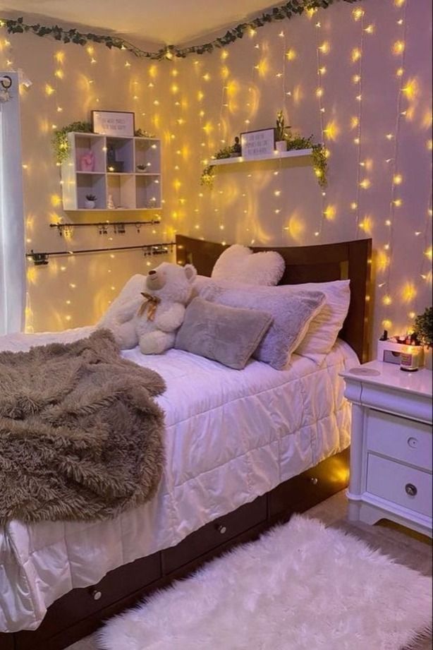 a bedroom decorated in white with lights and fur rugs on the bed, along with teddy bears