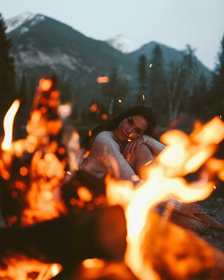 a woman sitting in front of a campfire