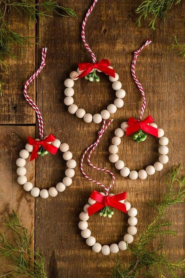 christmas decorations made out of beads and candy canes on a wooden table with greenery