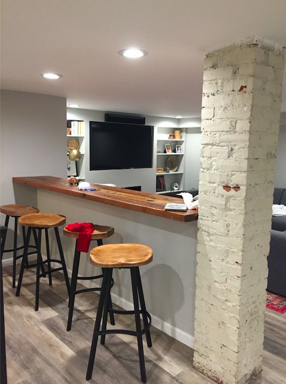 a bar with three stools and a television mounted on the wall