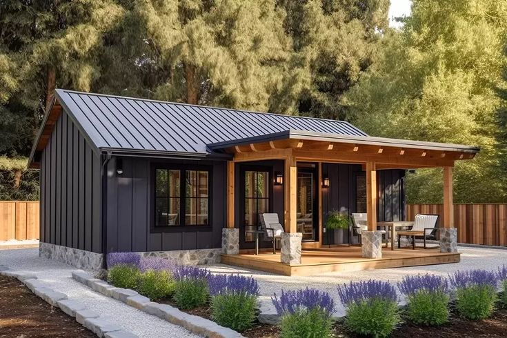 a small house with a covered patio and seating area in the middle of some trees