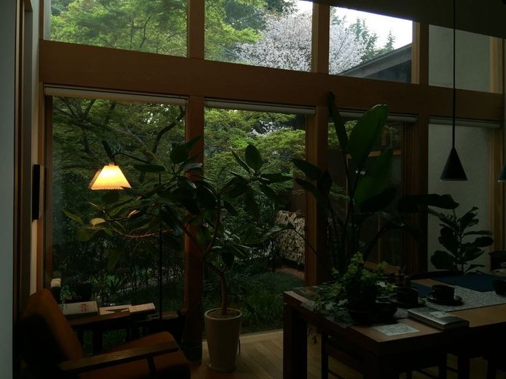 a living room filled with furniture and a large window next to a plant covered wall