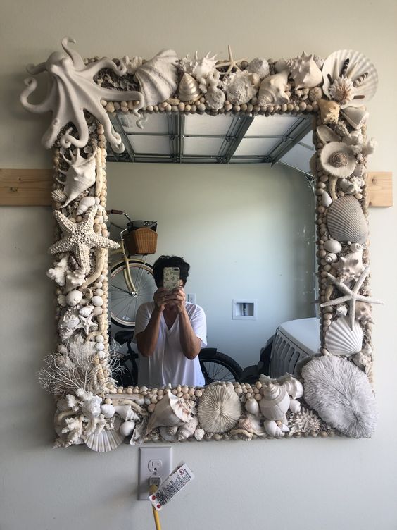 a person taking a selfie in front of a mirror with seashells on it